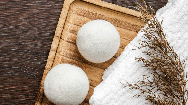 Two wool dryer balls on wooden tray—How long do essential oils last on dryer balls?